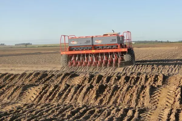 Foto de la sembradora mecánica SDM en un campo de arroz cruzando taipas.