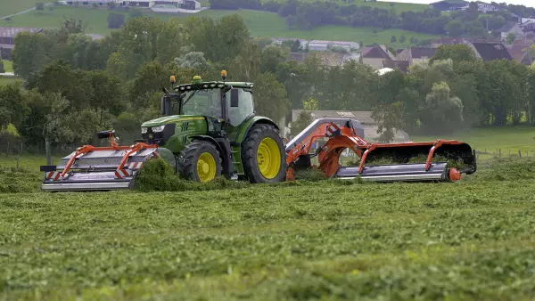 El hilerador de cinta frontal MERGE MAXX 440 F acoplado a un hilerador de cinta trasero MERGE MAXX 950 trabajando en una parcela.