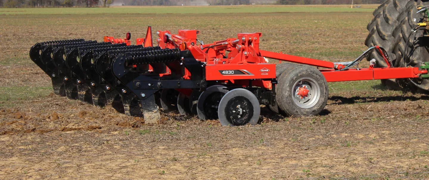 A side view of a KUHN 4830 trailed in-line ripper working the ground.