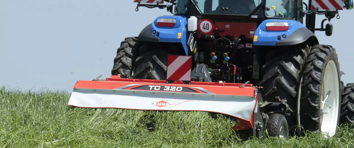 The TC 320 conditioner working in long grass on a tractor with duals.