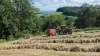 KUHN FB 3125 fixed round baler is baling round bales of silage in a field with large swaths