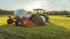 RW 1610 bale trailed round bale wrapper loading a round bale during wrapping of another bale.