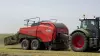 Large square baler baling in a straw field