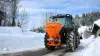 Distributeur VSA de sel, sable en action sur la route en montagne dans la neige